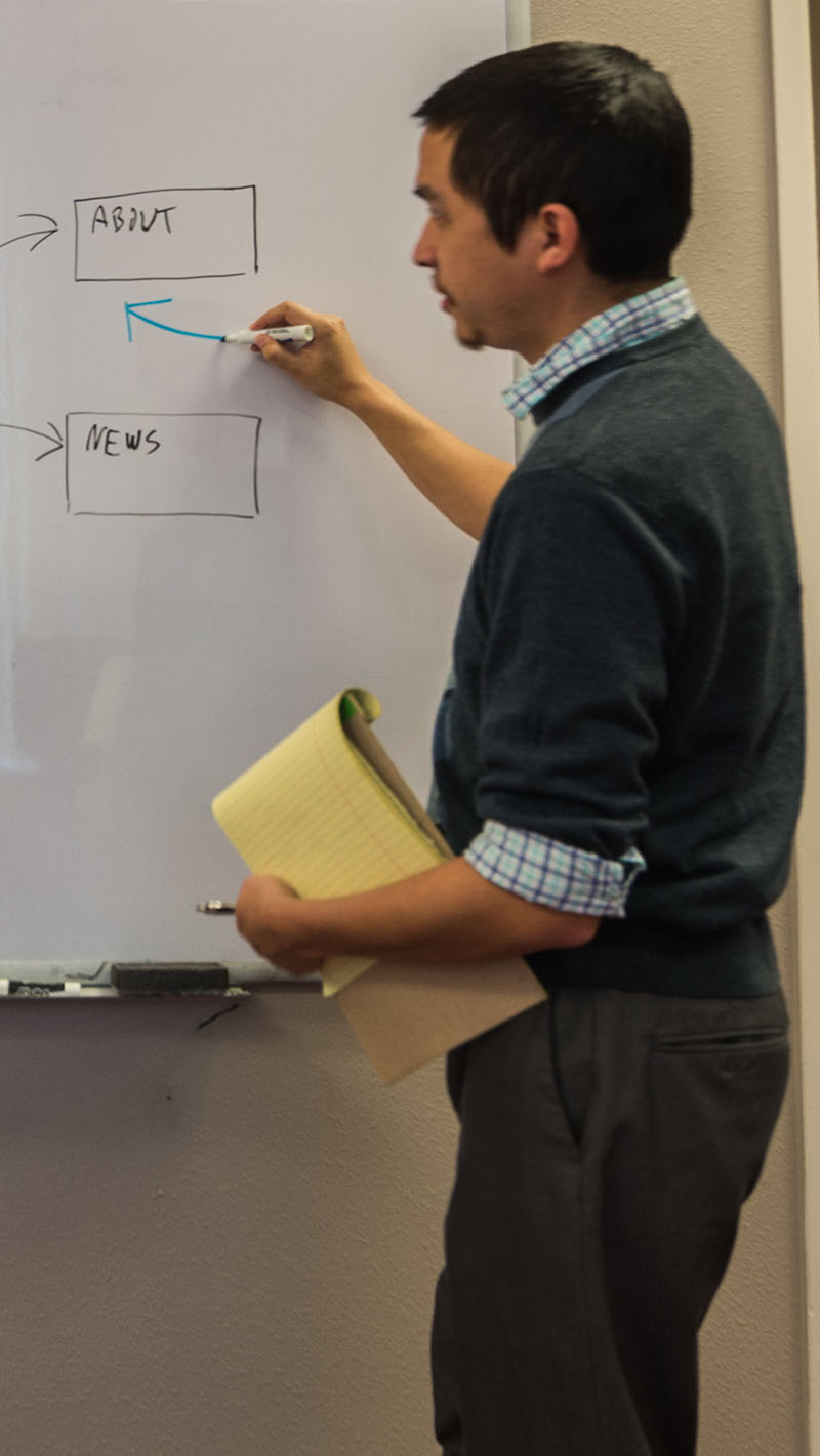 Photo of an online advertising expert on Capitol Tech Solutions' team brainstorming ideas on a white board.