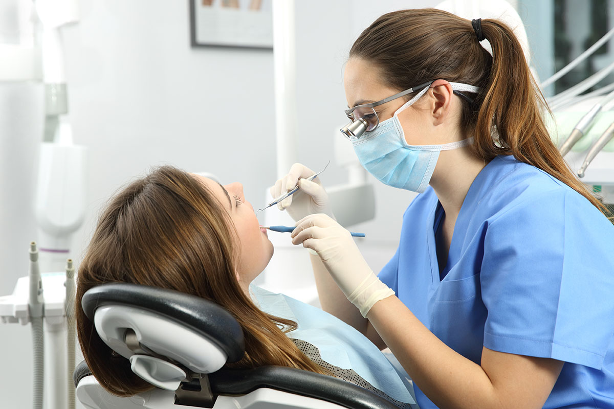 Photo of dentist examining a patient’s teeth at a dental office.