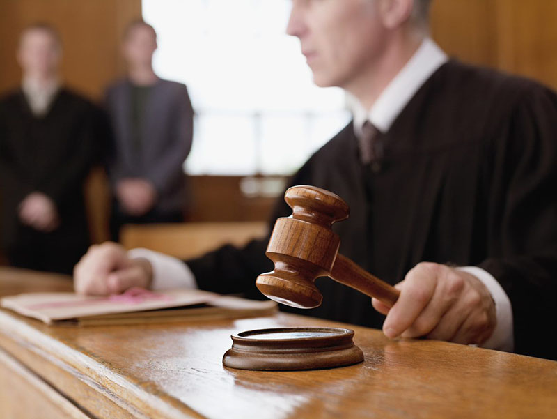 Photo of a lawyer speaking with a judge during court.