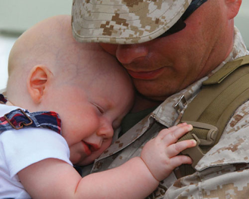 Photo of a US Army soldier hugging his infant child.