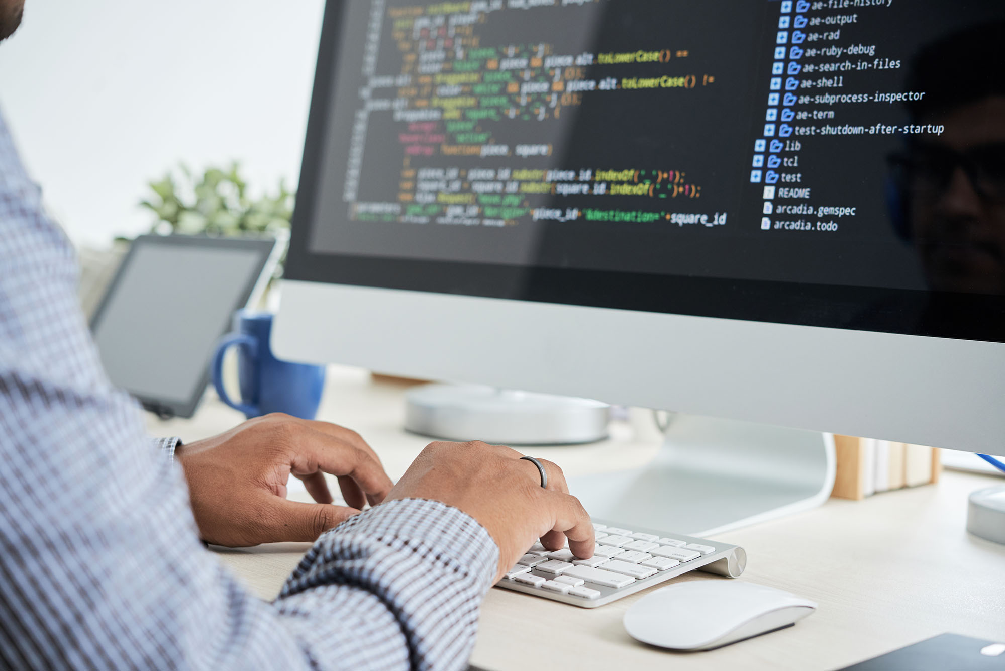 A software developer writes code at a desktop computer
