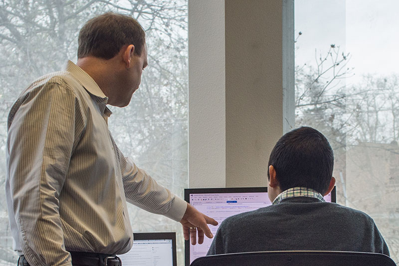 Two Capitol Tech Solutions content marketing team members look at a project on a desktop monitor