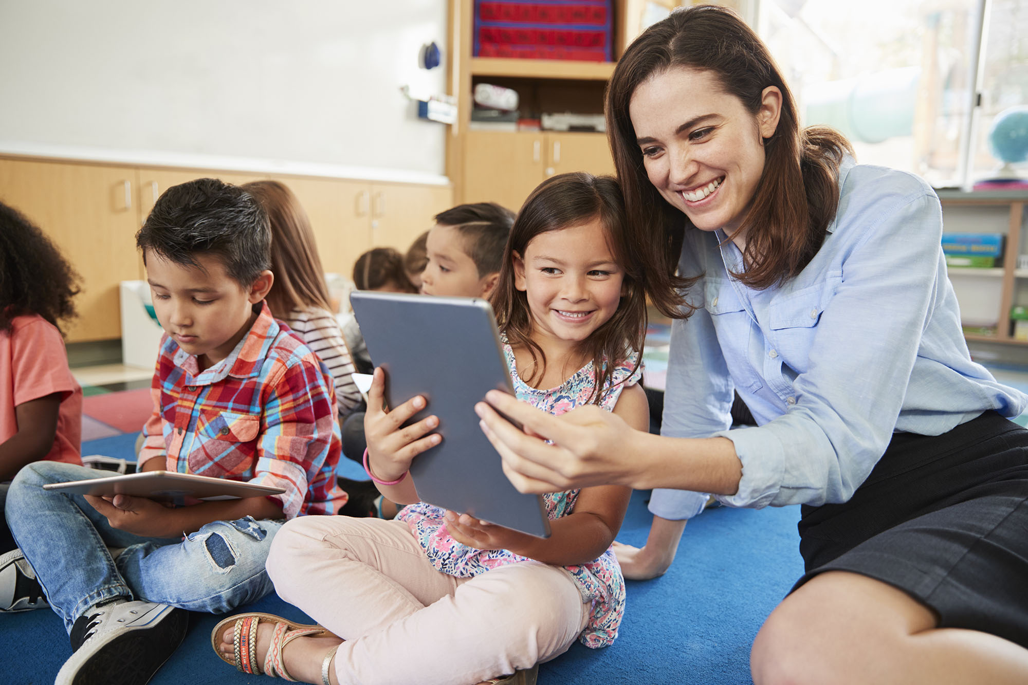 Photo of elementary school teacher using tablet with student